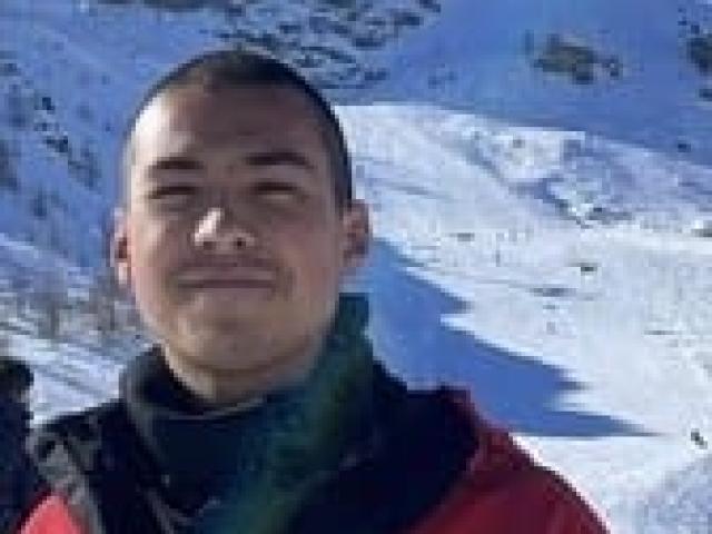Person smiling in dark jacket on snowy mountain ski slope